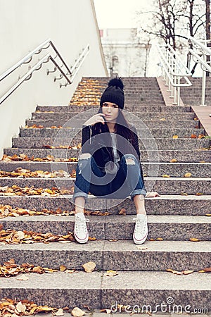 Teen girl sitting on stairs against grunge wall
