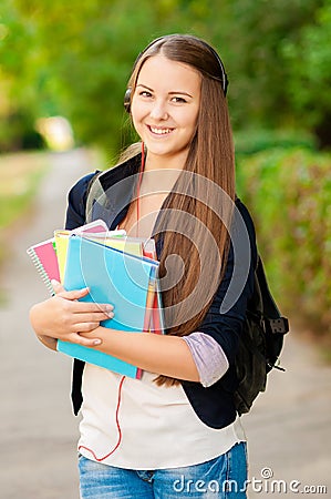 Teen student girl with books and a backpack in hands