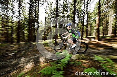 Teenage boy biking on forest trails