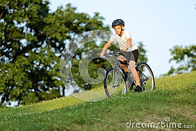 Teenage boy rides a bike from the hill in city park