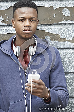 Teenage Boy Wearing Headphones And Listening To Music In Urban S