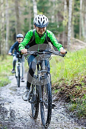 Teenage girl and boy biking on forest trails