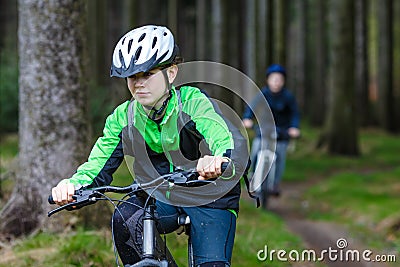 Teenage girl and boy biking on forest trails