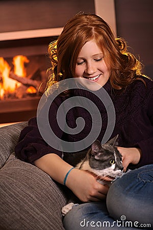 Teenage girl fondling cat at home