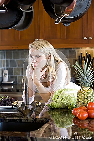 Teenage girl leaning on kitchen counter thinking