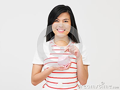 Teenage Girl Putting Money Into Piggy Bank