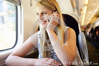 Teenage Girl Using Mobile Phone On Train Journey