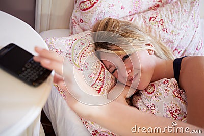 Teenage Girl Waking Up In Bed And Turning Off Alarm On Phone