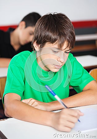 Teenage Schoolboy Writing At Desk During