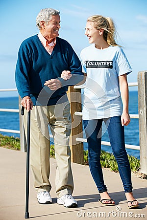 Teenage Volunteer Helping Senior Man Walking
