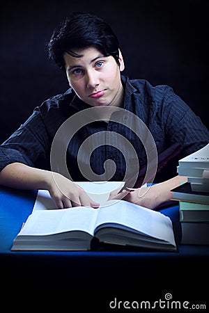 Teenager male doing homework by books with feather