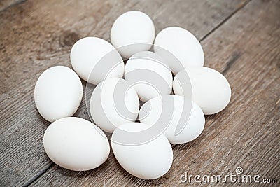 Ten chicken white eggs are on wooden floor