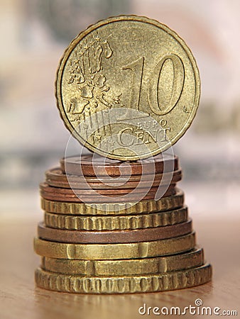 Ten euro cent coin balancing on a top of coins stack.