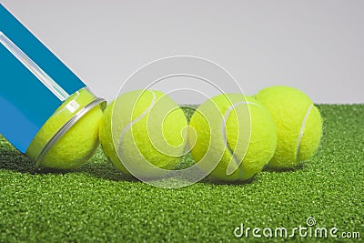Tennis concept: tennis balls out of a container lie on green art