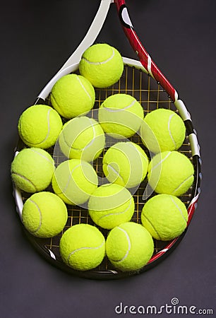 Tennis Racket with a lot of Tennis balls on it