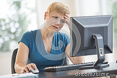 Tensed Businesswoman Using Computer At Desk