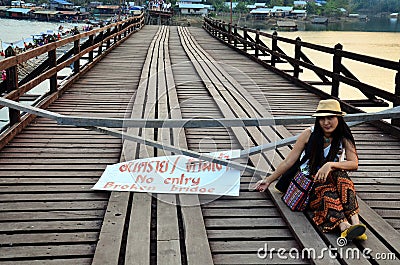 Thai women sitting on Broken Mon Bridge in Sangkhl