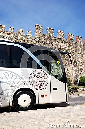 The modern bus for tourists transportation is near Byzantine city walls