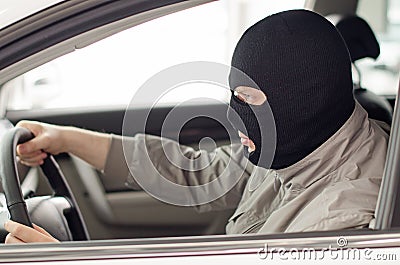 Thief in mask steals car.