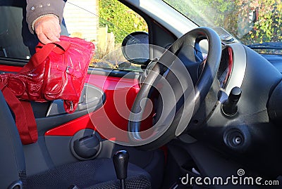 Thief stealing a handbag from a vehicle or automobile.