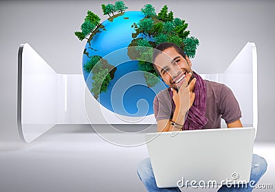 Thinking man sitting on floor using laptop and smiling