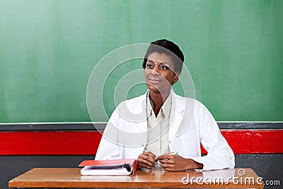 Thoughtful Female Teacher Sitting At Desk In