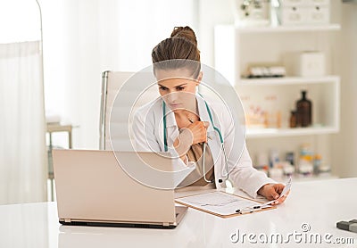 Thoughtful medical doctor woman looking in laptop