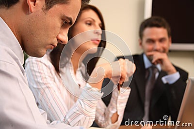 Three business persons working together with laptop in sunny office