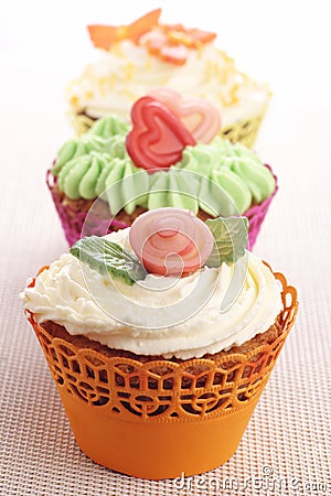 Three cupcakes with marzipan decorations.