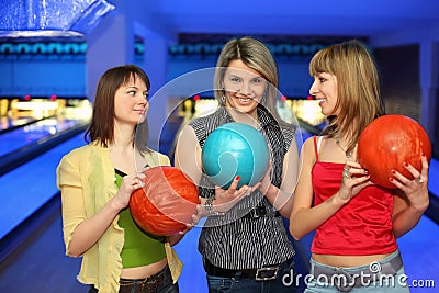 Three girlfriends hold balls for bowling