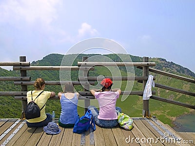 Three girls sitting on observation deck looking at mountains