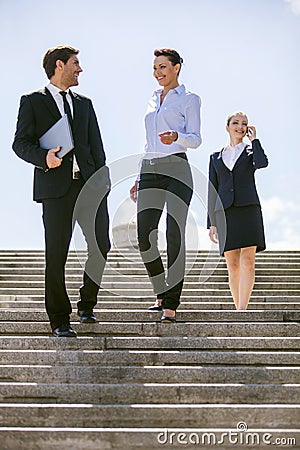 Three happy business people walking together outside.