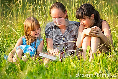 Three little sister reading book in natural