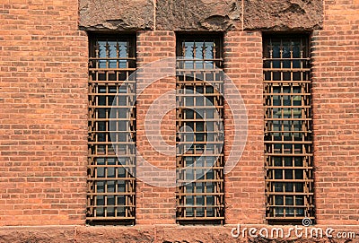 Three long barred windows in old brick wall