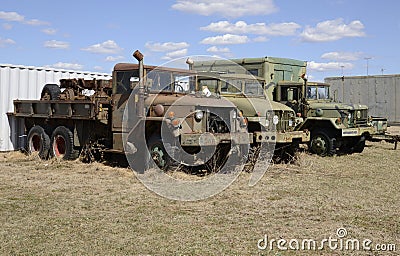 Three old army vehicles parked in a grass field