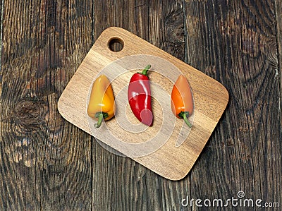 Three peppers on a board.