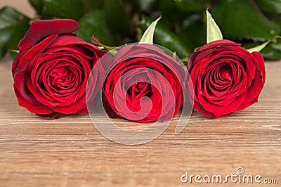 Three red roses on wood