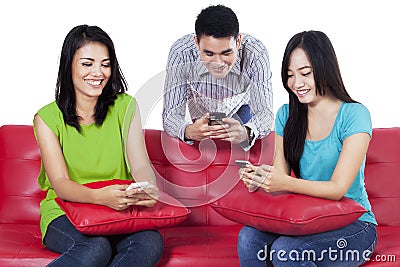 Three teenagers typing sms