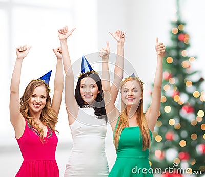 Three women wearing hats and showing thumbs up