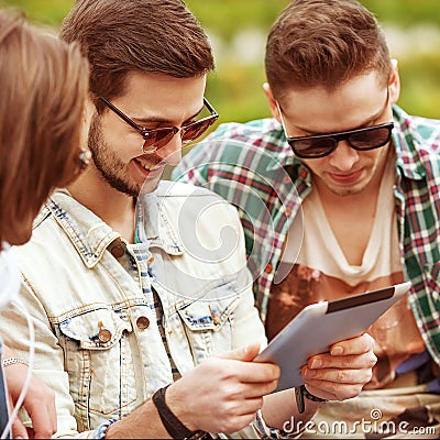 Three young men friends using tablet