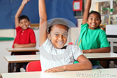 Three young school children arms raised in class