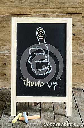 Thumb up Chalkboard Drawing on wooden background.