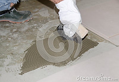 Tiler spreading tile adhesive on the floor