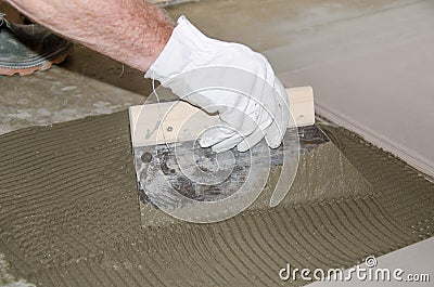 Tiler spreading tile adhesive on the floor