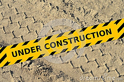 Tire track in a sand with under construction yellow tape