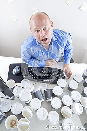 Tired businessman drinks too much coffee at office