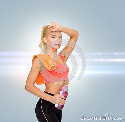 Tired sporty woman with towel and water bottle