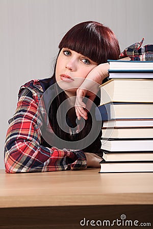 Tired student girl resting on stack of books