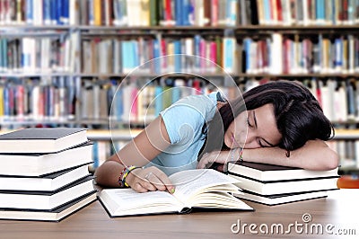 Tired student sleeping at the desk in a library