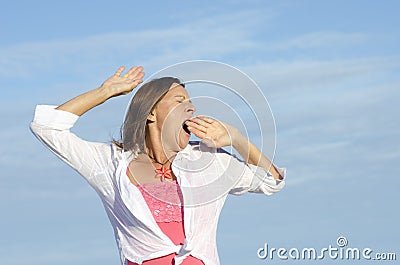 Tired woman yawning sky background
